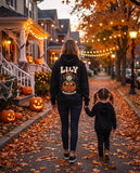 Mom seen from behind in a black hoodie with her child's Halloween portrait on the back
