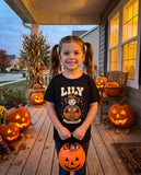 Little girl on a Halloween porch wearing her custom kid portrait t-shirt with a pumpkin candy bucket