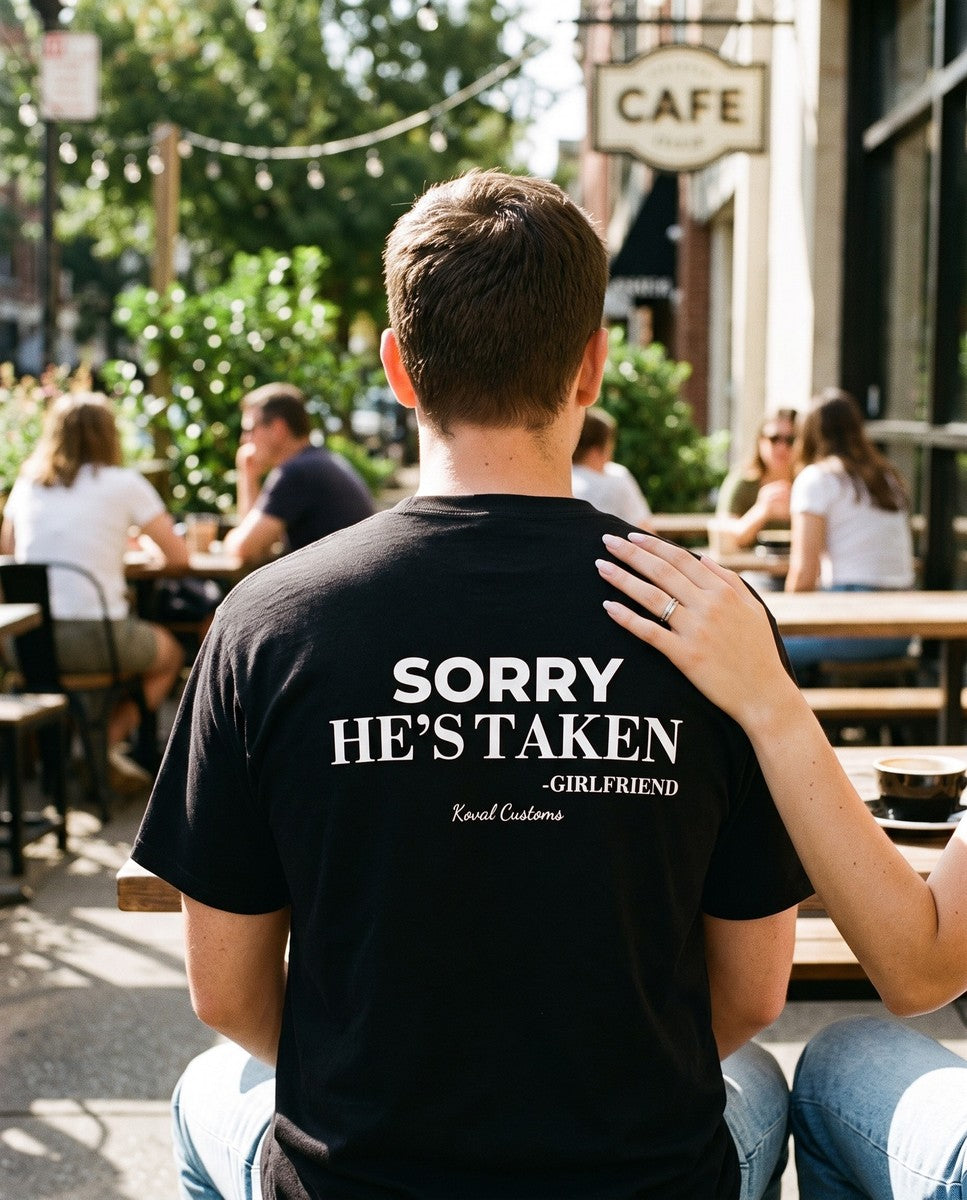 Man seen from behind wearing the black Sorry He's Taken t-shirt
