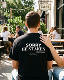 Man seen from behind wearing the black Sorry He's Taken t-shirt