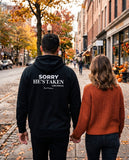 Man seen from behind wearing the black Sorry He's Taken hoodie