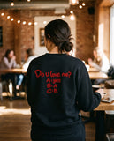 Person wearing the black Do U Love Me crewneck sweatshirt, seen from behind