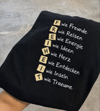 [DE] Nahaufnahme der Stickerei mit Würfelbuchstaben FREIHEIT: wie Freunde, Reisen, Energie, Ideen, Herz, Entdecken, Inseln, Träume