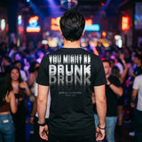 Man in a nightclub in a black t-shirt with a motion-blur You Might Be Drunk print across the back