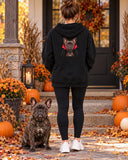 Woman on an autumn porch wearing the black hoodie with her French bulldog vampire portrait, the dog sitting next to her