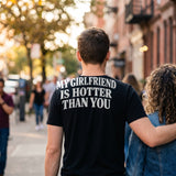Man walking with his girlfriend in a black t-shirt with My Girlfriend Is Hotter Than You printed across the back