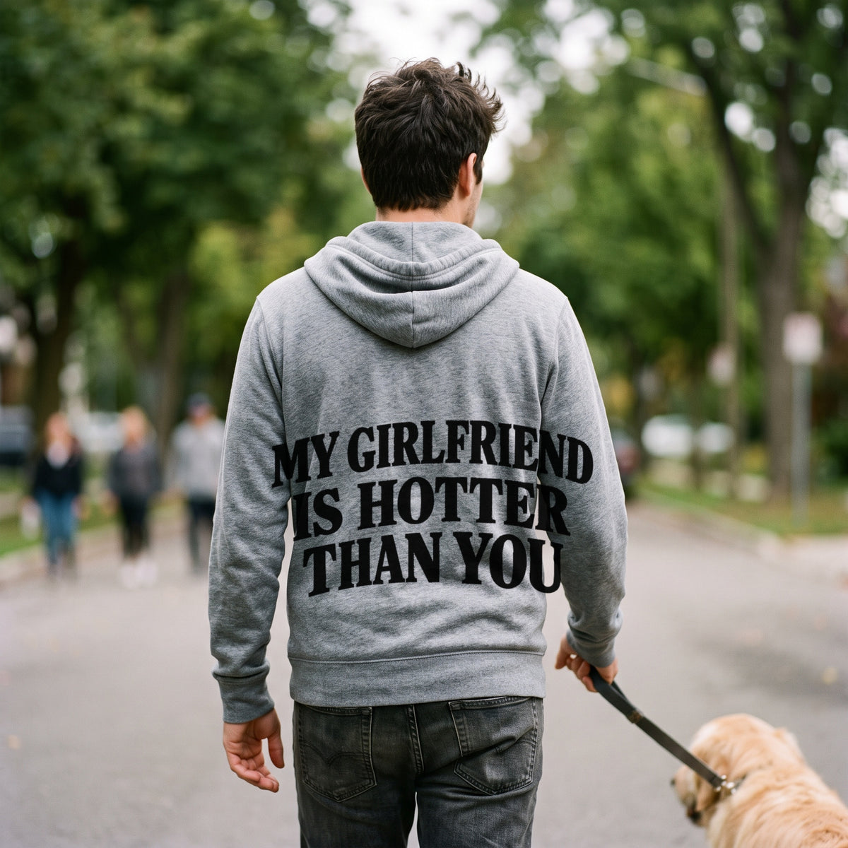 Man walking a dog in a sport grey zip hoodie with My Girlfriend Is Hotter Than You printed across the back