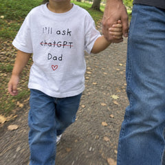 Child in an I'll ask chatGPT Dad T-shirt holding dad's hand in the park