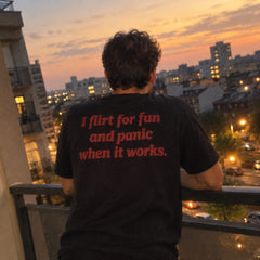 Black T-shirt with red I flirt for fun and panic when it works back print, on a balcony at night