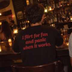 Black I flirt for fun and panic when it works T-shirt with back print, at a bar