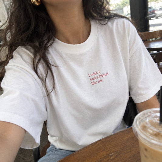 White T-shirt with a small I wish I had a friend like me chest print, in a cafe